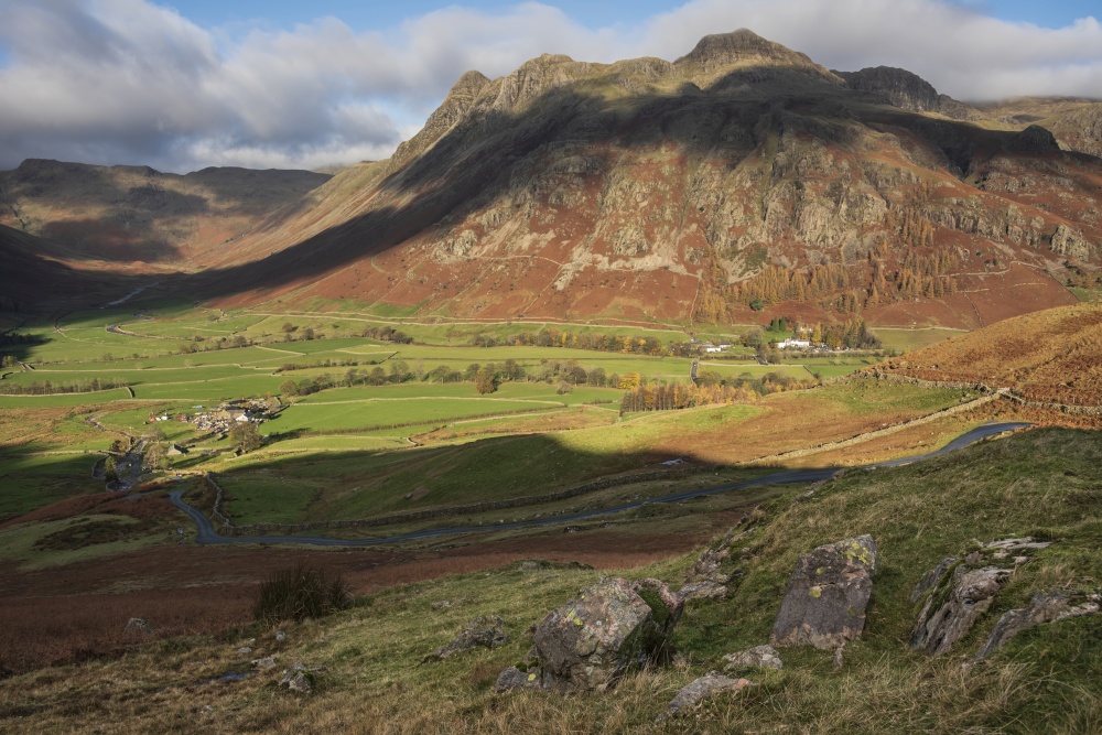 Stunning vibrant Autumn landscape image looking from Pike O&rsquo;Blisco towards Langdale Pikes and Range with beautiful sungiht on mountains and valley