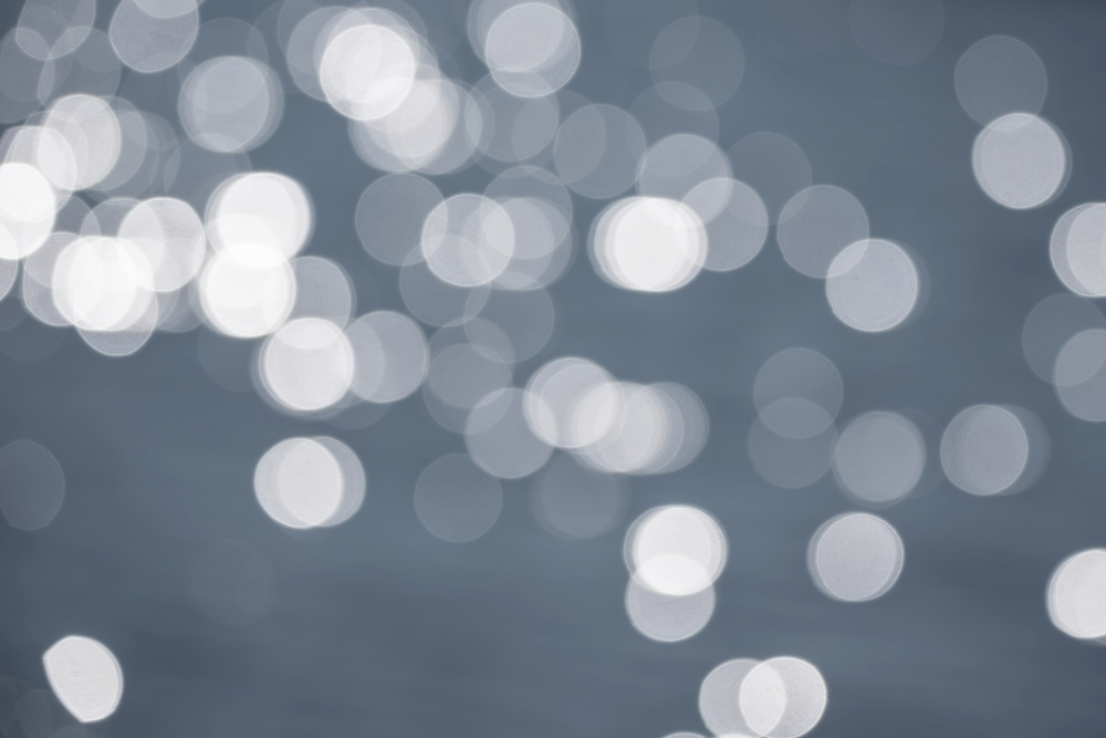 Beautiful blurred bokeh effect image of specular highlights on lake during Summer sunny day