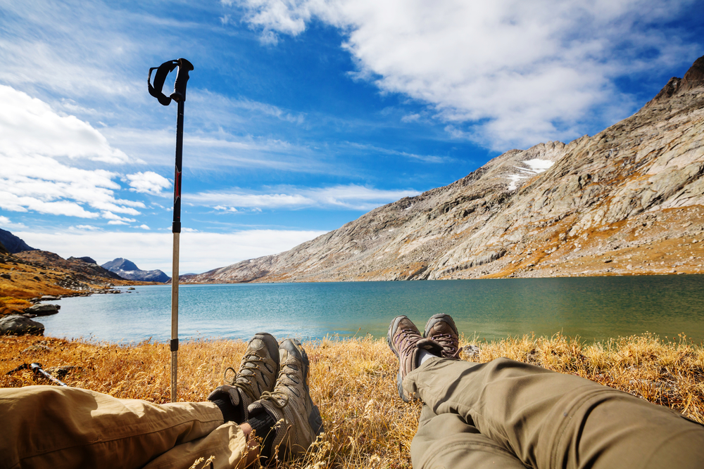 Traveler couple relaxing after hiking near mountains lake.