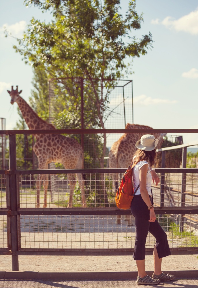 Young woman near giraffe in Zoo