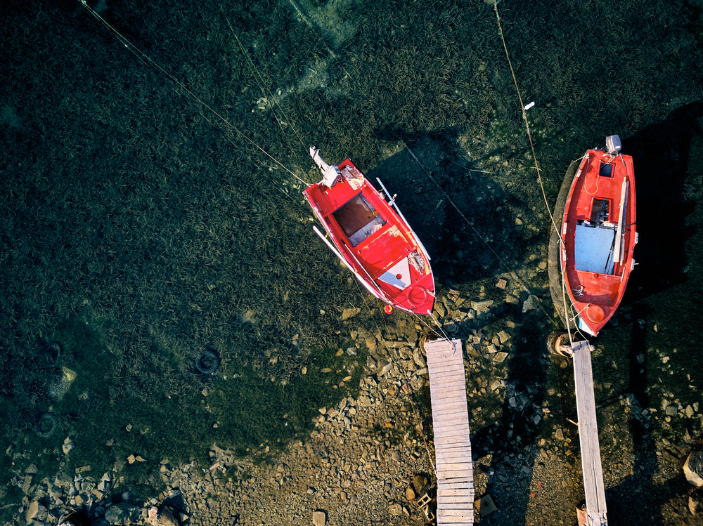 Wooden pier with fishing boats top aerial view drone shot, Sithonia, Greece
