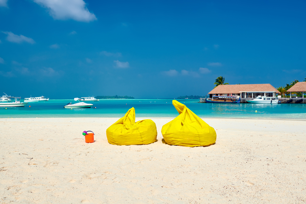 Tropical beach with yellow beanbag chairs. Summer vacation at Maldives.