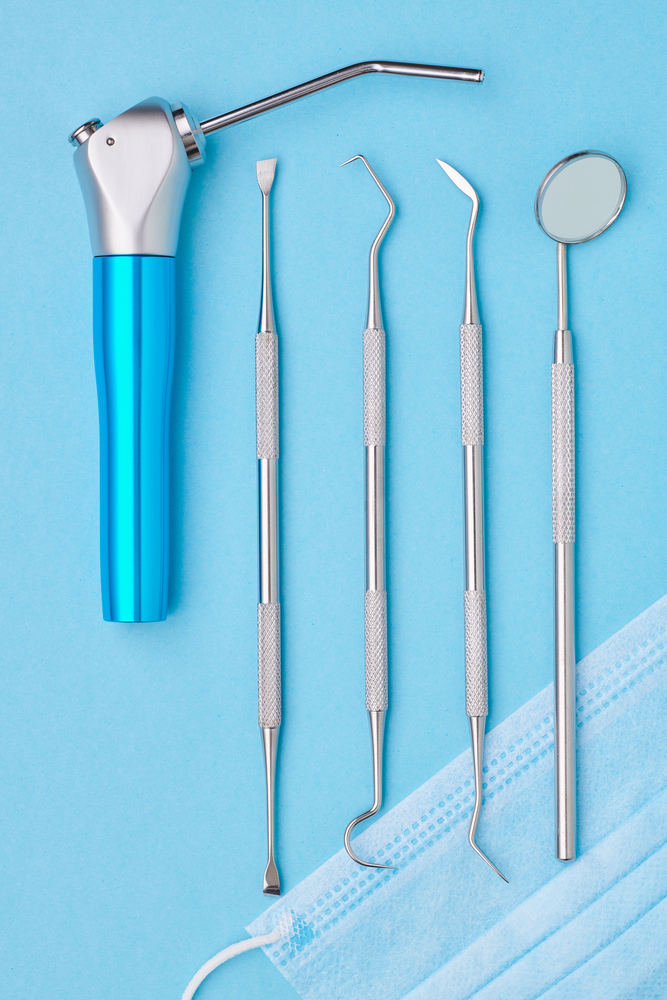 Dentist tools over light blue background top view flat lay. Tooth care, dental hygiene and health concept.