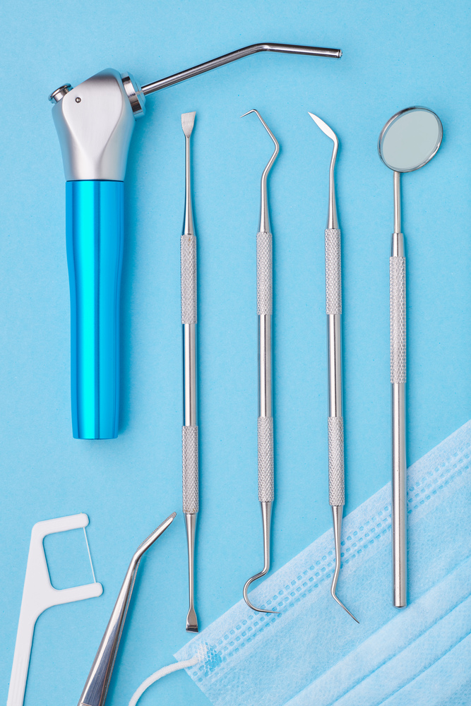 Dentist tools over light blue background top view flat lay. Tooth care, dental hygiene and health concept.