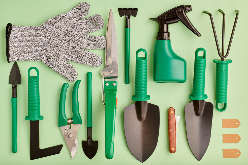 Gardening tools on green background flat lay top view