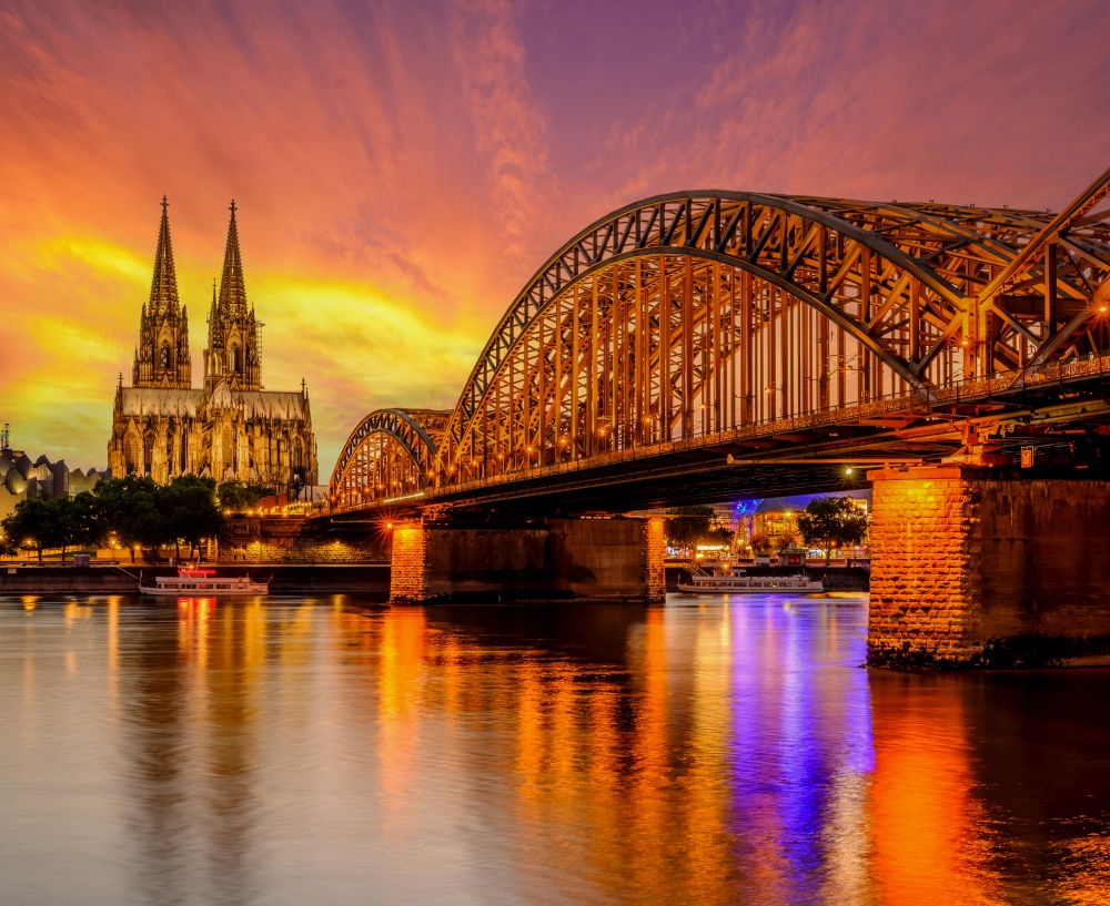 Night View of Cologne Cathedral (Kolner Dom) and Rhine river under the Hohenzollern Bridge at sunset, Cologne city skyline at night, North Rhine Westphalia region, Germany.