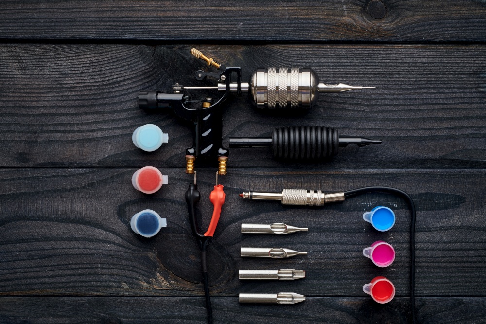 Tattoo machine, tools and supplies over wooden background. Tattoo studio.