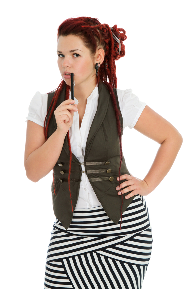 Beautiful young accountant with pen wearing vest and striped skirt isolated on white background.