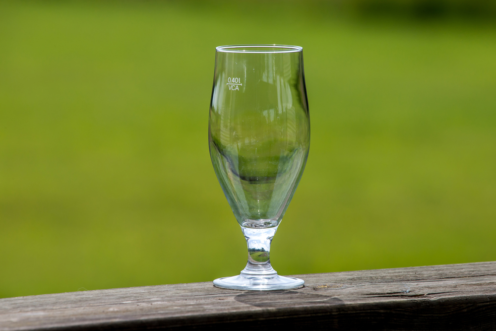 Empty glass of beer on wooden table on green nature background. Empty glass of beer on green nature background.