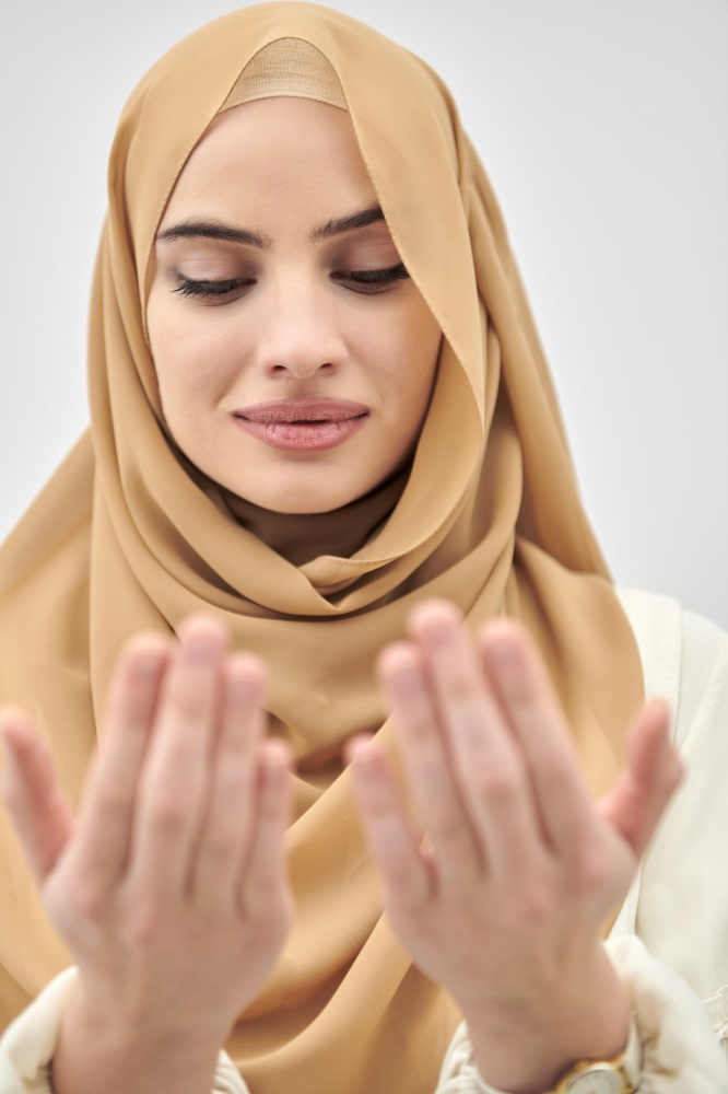 Portrait of young muslim woman making dua, praying to God. Girl wearing modern and fashionable dress isolated on white background