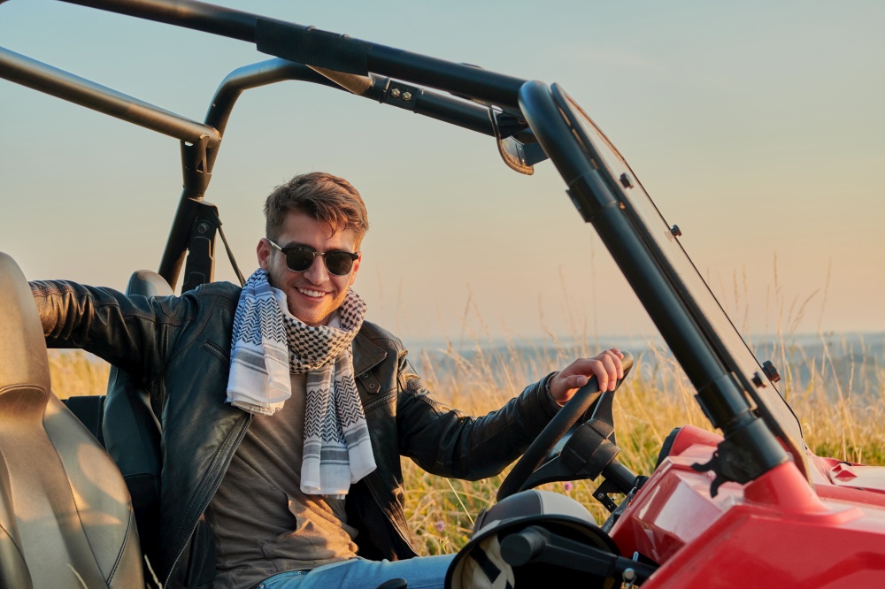 portrait of young happy excited man enjoying beautiful sunny day while driving a off road buggy car on mountain nature