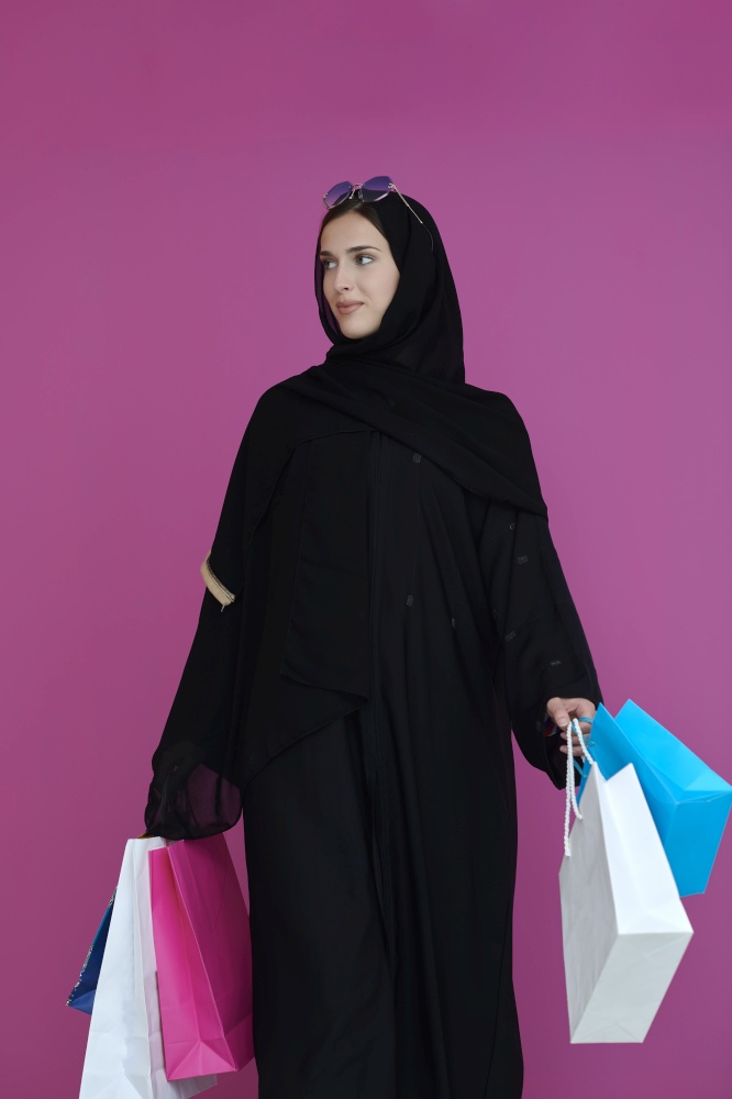Happy muslim girl posing with shopping bags. Arabic woman wearing traditional black clothes and sunglasses representing rich and  luxurious lifestyle