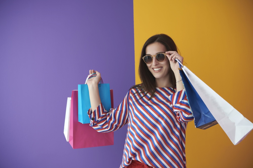 Young woman with shopping bags on colorful background. Happy girl posing with new purchases after a day of big sale. Black Friday concept