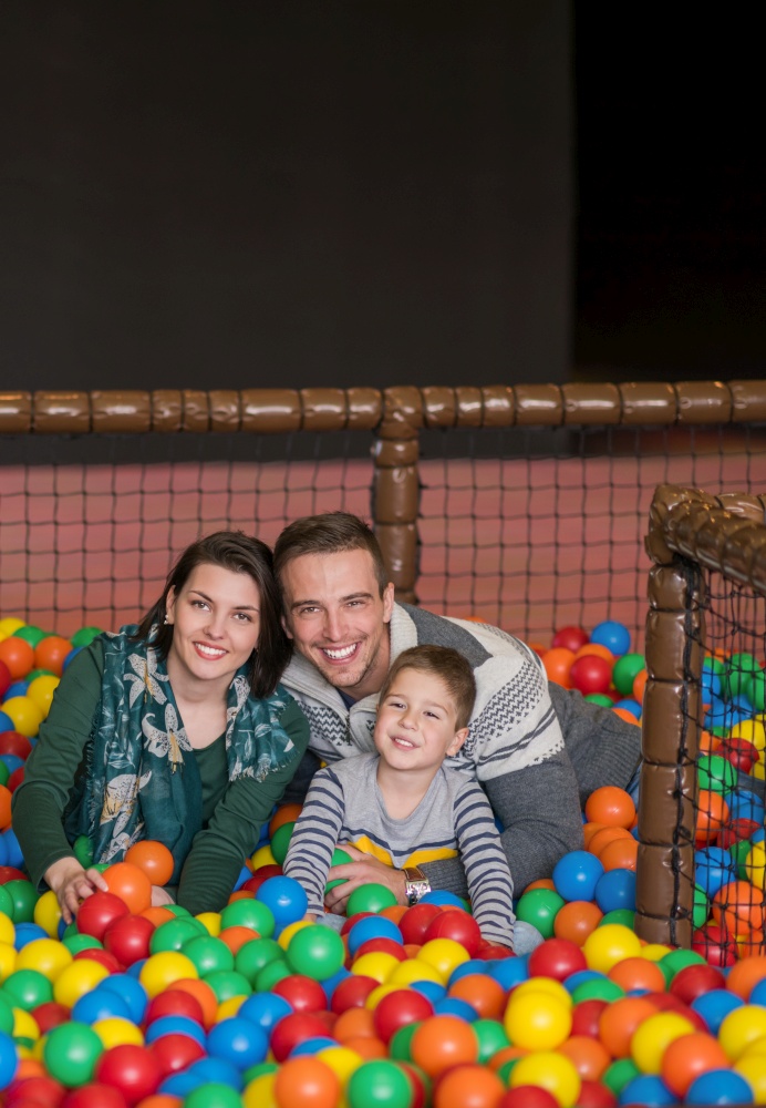 happy family enjoying free time young parents and kids playing in the pool with colorful balls at childrens playroom