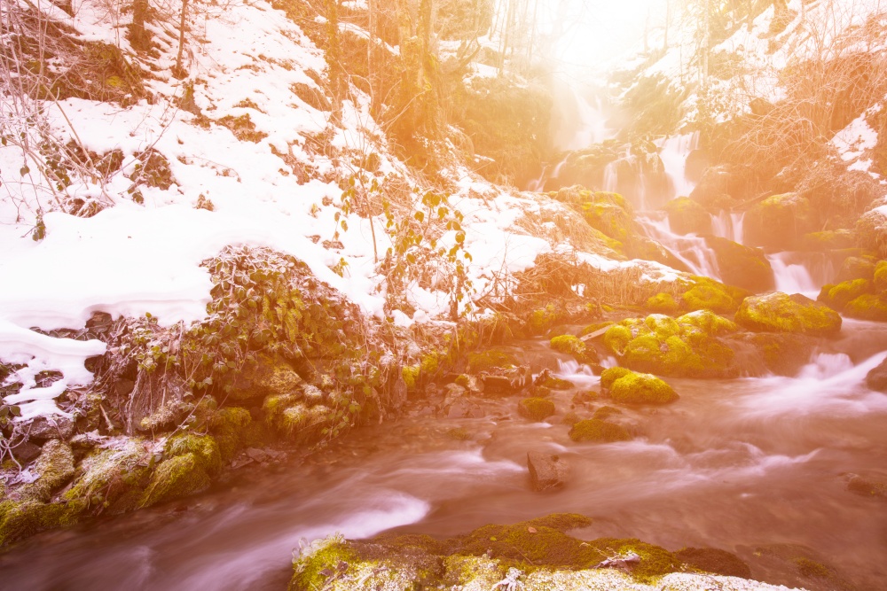 Amazing nature landscape, beautiful waterfall with sunlight in deep winter forest