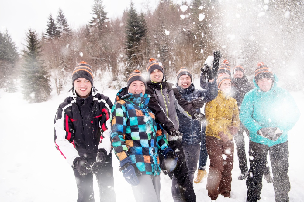 group of young happy business people having fun throwing snow in the air while enjoying snowy winter day with snowflakes around them during a team building in the mountain forest
