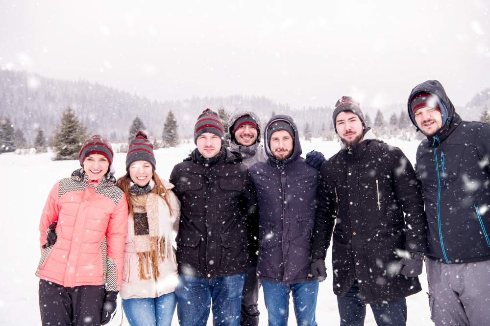 group portrait of young happy business people enjoying snowy winter day with snowflakes around them during a team building in the mountain forest