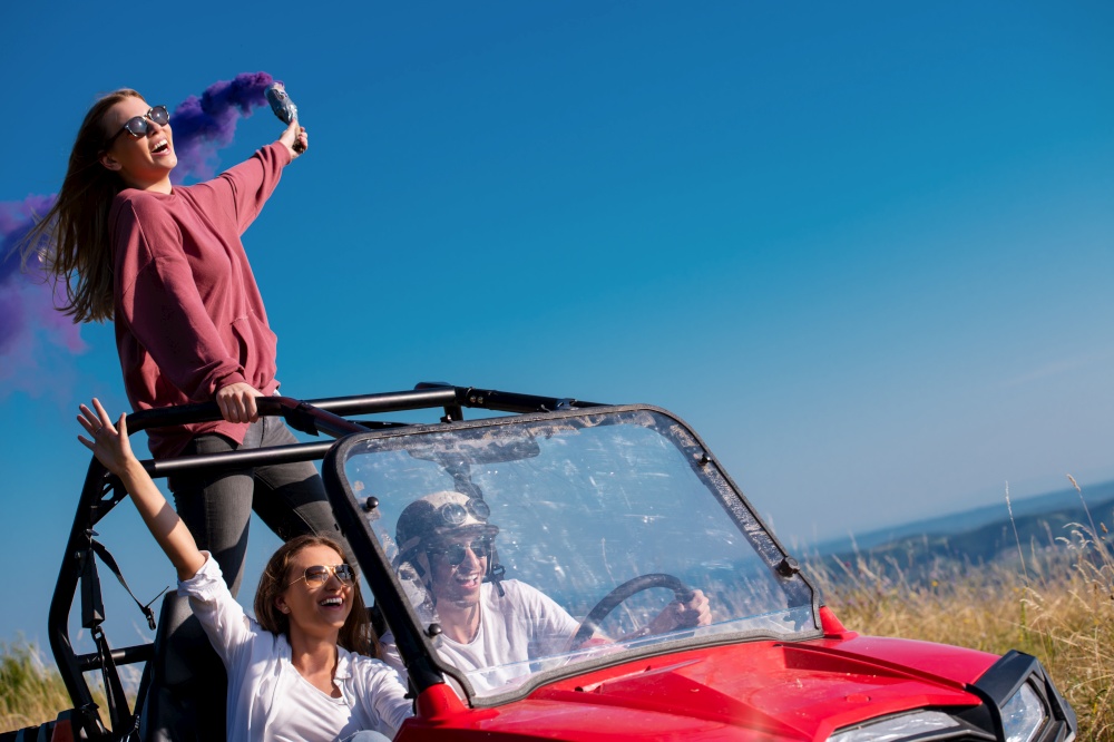 group of young happy excited people having fun enjoying beautiful sunny day holding colorful torches while driving a off road buggy car on mountain nature