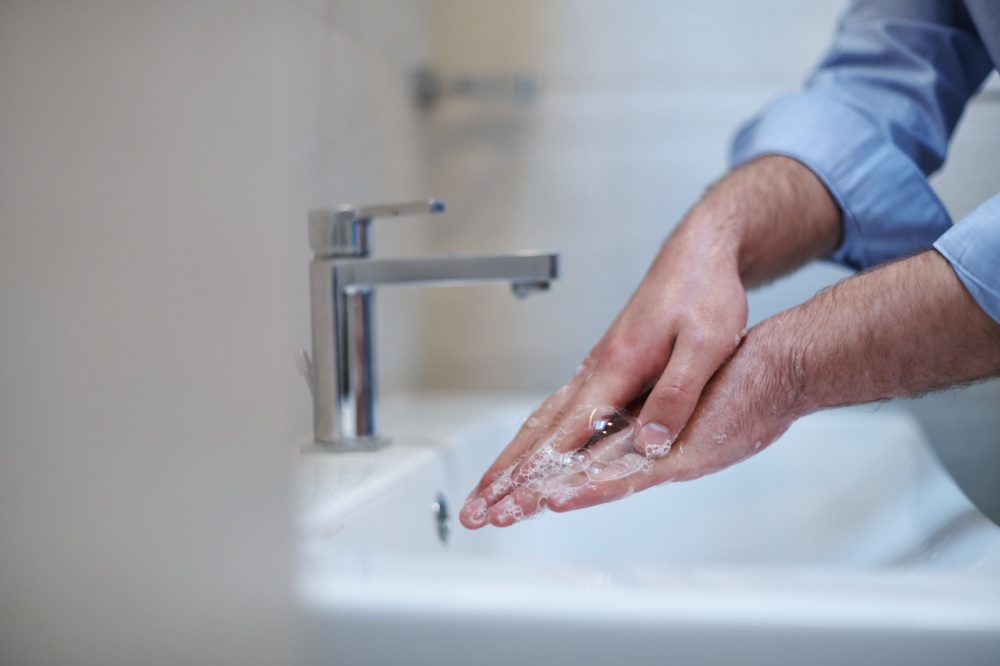 Coronavirus infection and spreading prevention, proper Washing hands with liquid soap. Hygiene male antibacterial hands water wash closeup in bathroom.