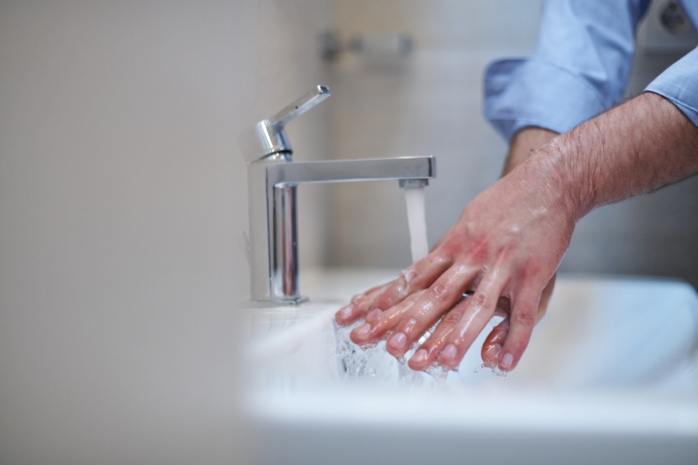 Coronavirus infection and spreading prevention, proper Washing hands with liquid soap. Hygiene male antibacterial hands water wash closeup in bathroom.