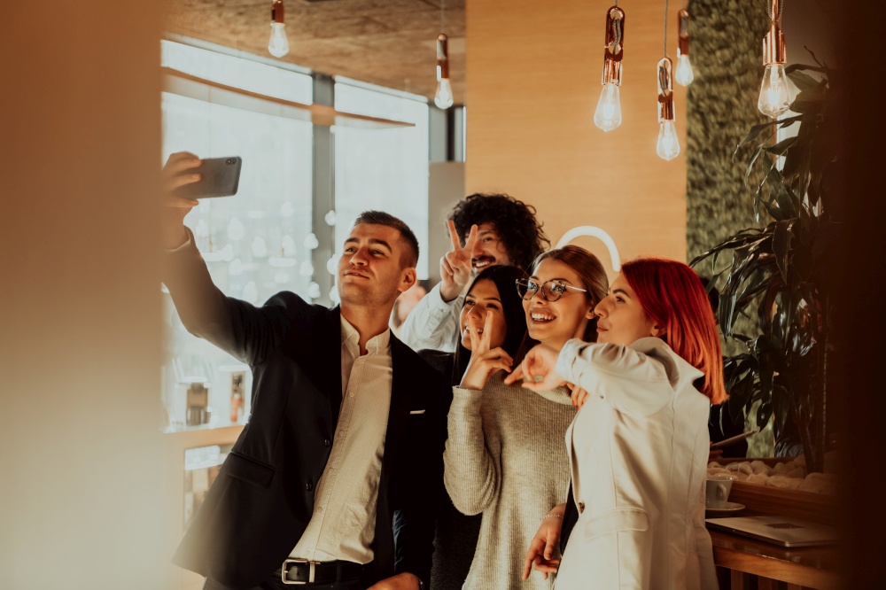 Business people taking selfies in the office. The business team taking a selfie together at startup. Group of cheerful colleagues taking selfie and gesturing while standing in the modern office.