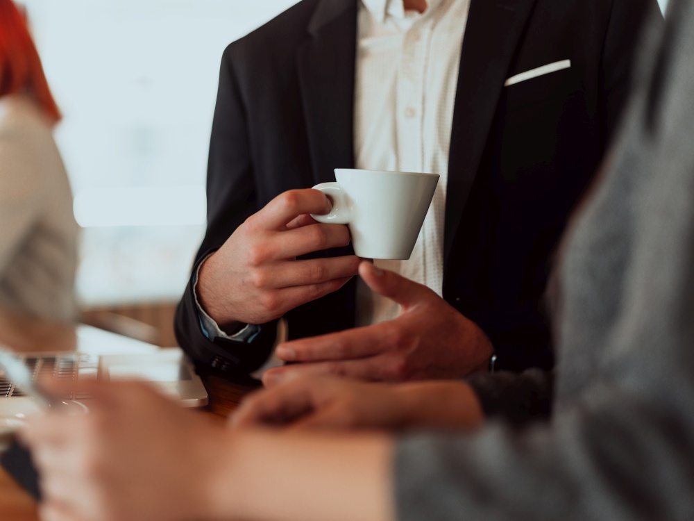 macro photo of a businessman in a suit holding a cup of coffee. macro photo of a businessman in a cafe in a suit holding a cup of coffee.