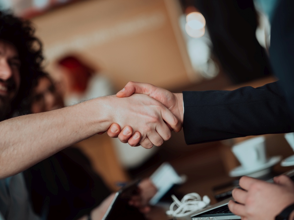 Business people or lawyers shaking hands finishing up meeting or negotiation in sunny office. Business handshake and partnership. Business people or lawyers shaking hands finishing up meeting or negotiation in sunny office.