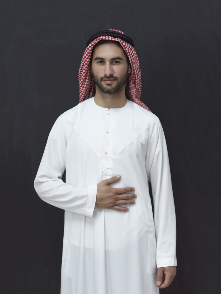 portrait of young arabian man in traditional clothes in front of black chalkboard representing modern islam fashion and ramadan kareem concept