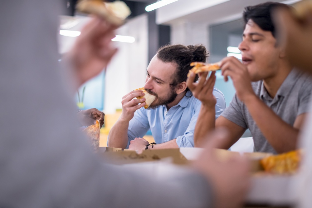 Friendly diverse multiethnic business team eating sharing pizza together in startup office, multiracial coworkers staff group enjoying break talking laughing on lunch time at meeting