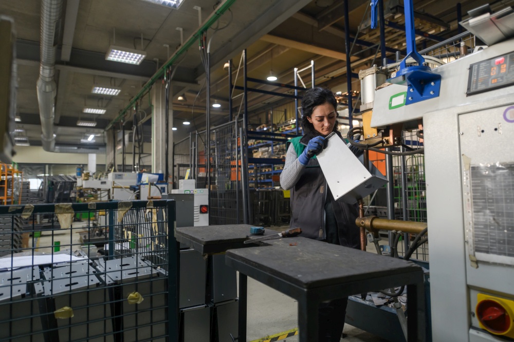 a woman working in a modern metal factory assembles parts for a new machine. High quality photo. a woman working in a modern metal factory assembles parts for a new machine