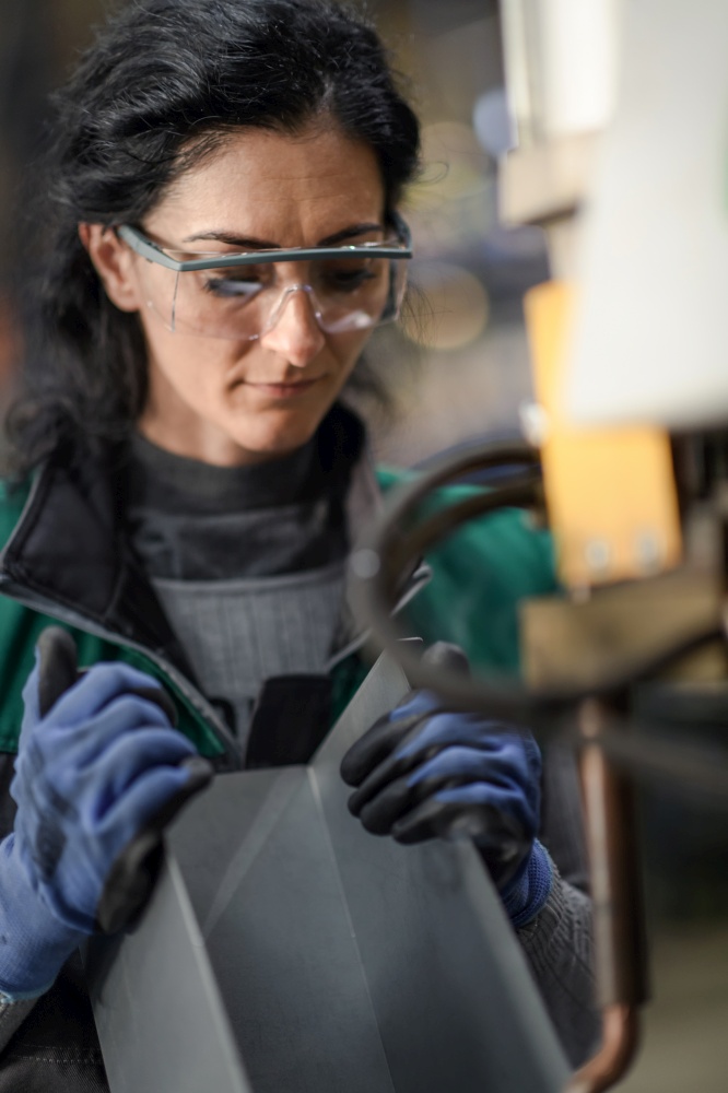 Woman worker wearing safety goggles control lathe machines to drill components. Metal lathe industrial manufacturing factory. High quality photo. Woman worker wearing safety goggles control lathe machine to drill components. Metal lathe industrial manufacturing factory