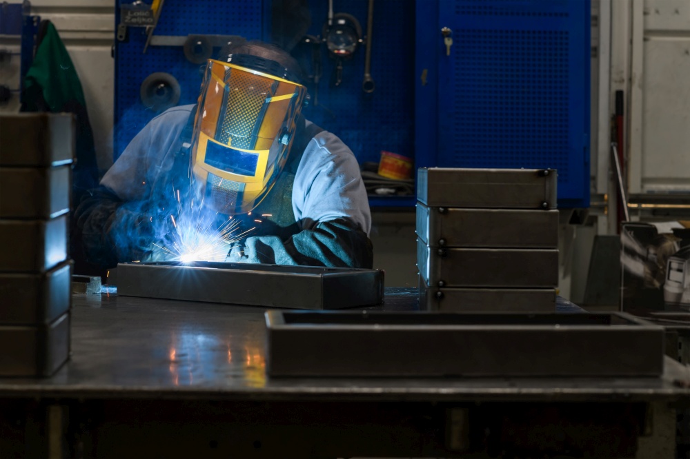 Professional welder performs work with metal parts in factories, sparks, and electricity. Industry worker banner. High quality photo. Professional welder performs work with metal parts in factory, sparks and electricity. Industry worker banner.