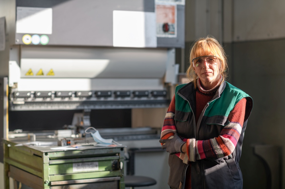 portrait of a woman standing in front of a CNC machine in goggles and working in a modern metal production and processing factory. High quality photo. portrait of a woman standing in front of a CNC machine in goggles and working in a modern metal production and processing factory