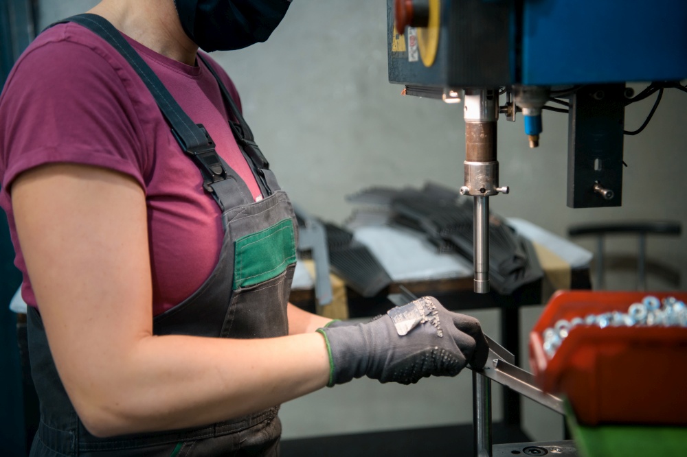 woman wearing a face mask due to coronavirus pandemic while working in the modern metal industry and using a drill. High quality photo. woman wearing mask due to coronavirus pandemic while working in modern metal industry and using drill