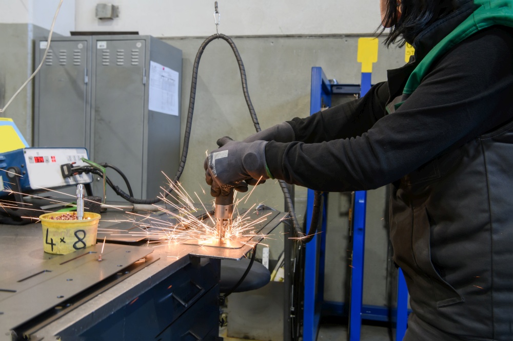 a woman working in the modern metal production and processing industry welds the product and prepares it for a CNC machine. High quality photo. a woman working in the modern metal production and processing industry welds the product and prepares it for a cnc machine