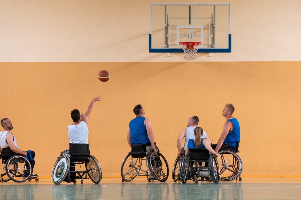 Disabled War veterans mixed race opposing basketball teams in wheelchairs photographed in action while playing an important match in a modern hall. High quality photo. Disabled War veterans mixed race opposing basketball teams in wheelchairs photographed in action while playing an important match in a modern hall.