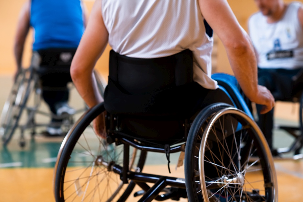 Close up photo of wheelchairs and handicapped war veterans playing basketball on the court. High quality photo. Close up photo of wheelchairs and handicapped war veterans playing basketball on the court