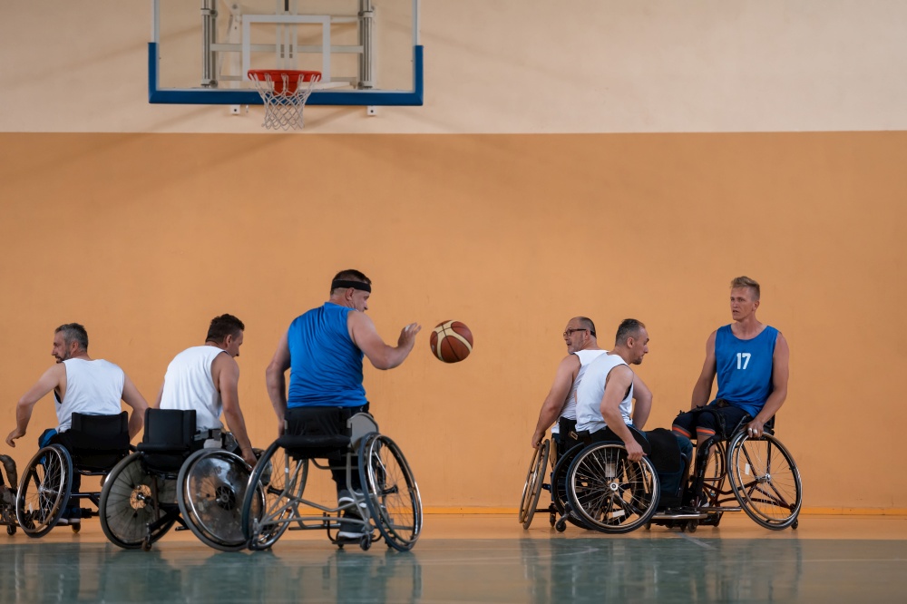 Disabled War veterans mixed race opposing basketball teams in wheelchairs photographed in action while playing an important match in a modern hall. High quality photo. Disabled War veterans mixed race opposing basketball teams in wheelchairs photographed in action while playing an important match in a modern hall.