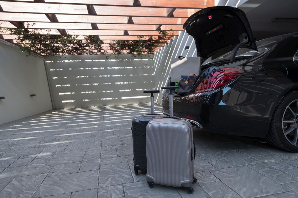 A photo of a suitcase standing next to a car in a luxury garage. High-quality photo. A photo of a suitcase standing next to a car in a luxury garage. Selective focus