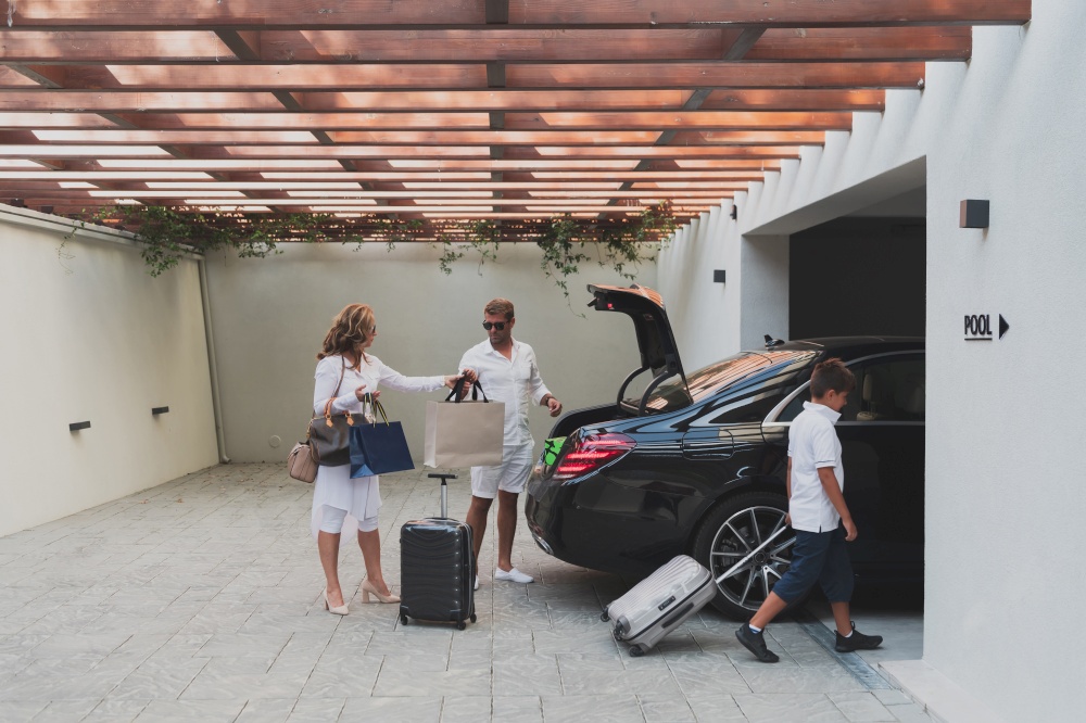 A photo of a modern family carrying suitcases from a garage to their luxury seaside home during a vacation. Vacation concept. Selective focus. High-quality photo. A photo of a modern family carrying suitcases from a garage to their luxury seaside home during a vacation. Vacation concept. Selective focus