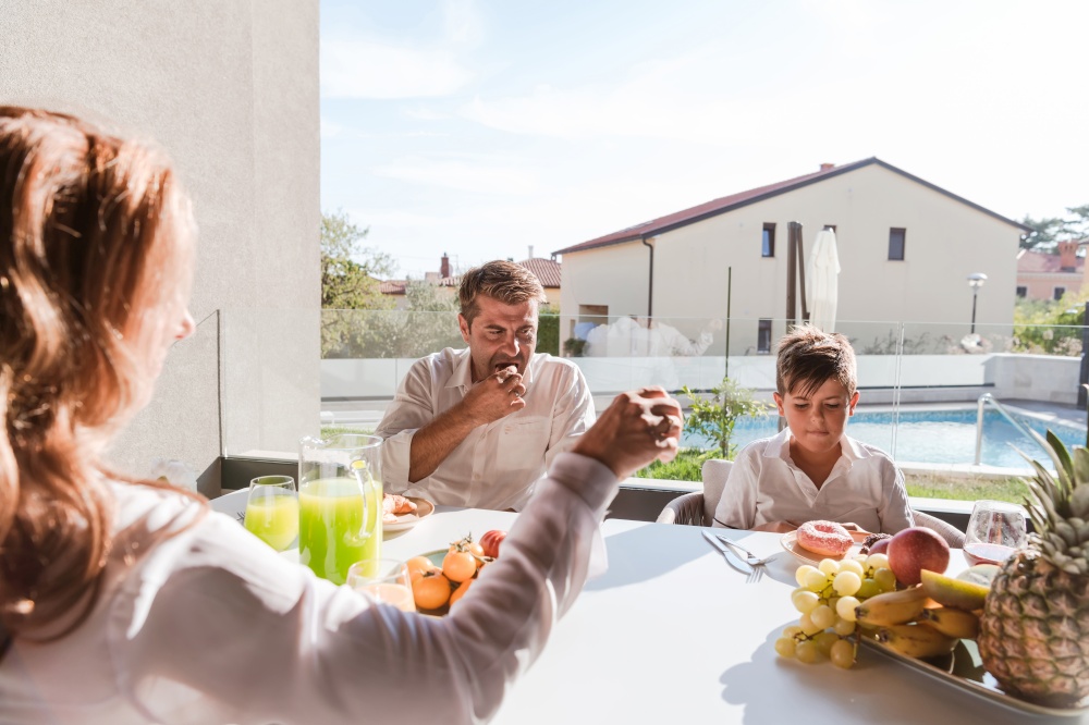 The senior couple and their son eating a healthy breakfast together early in the morning in a luxury house. Selective focus. High-quality photo. Senior couple and their son eating a healthy breakfast together early in the morning in a luxury house. Selective focus