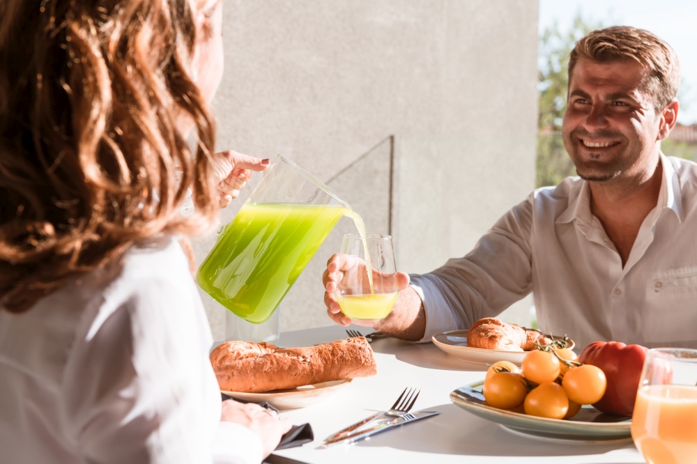Featuring a woman and man enjoying a wholesome breakfast together. Seated at a cosy table with fresh fruits and juice, sharing smiles and lively conversation.