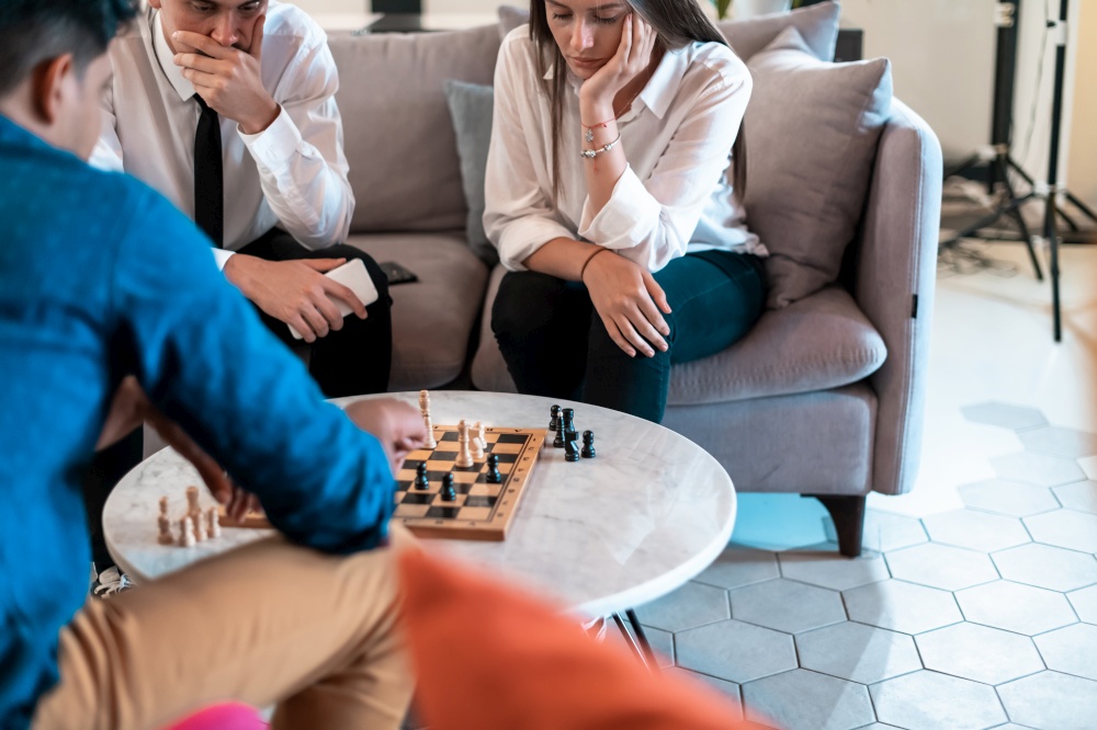 Multiethnic group of businesspeople playing chess while having a break in relaxation area at modern startup office. High-quality photo. Multiethnic group of business people playing chess while having a break in relaxation area at modern startup office