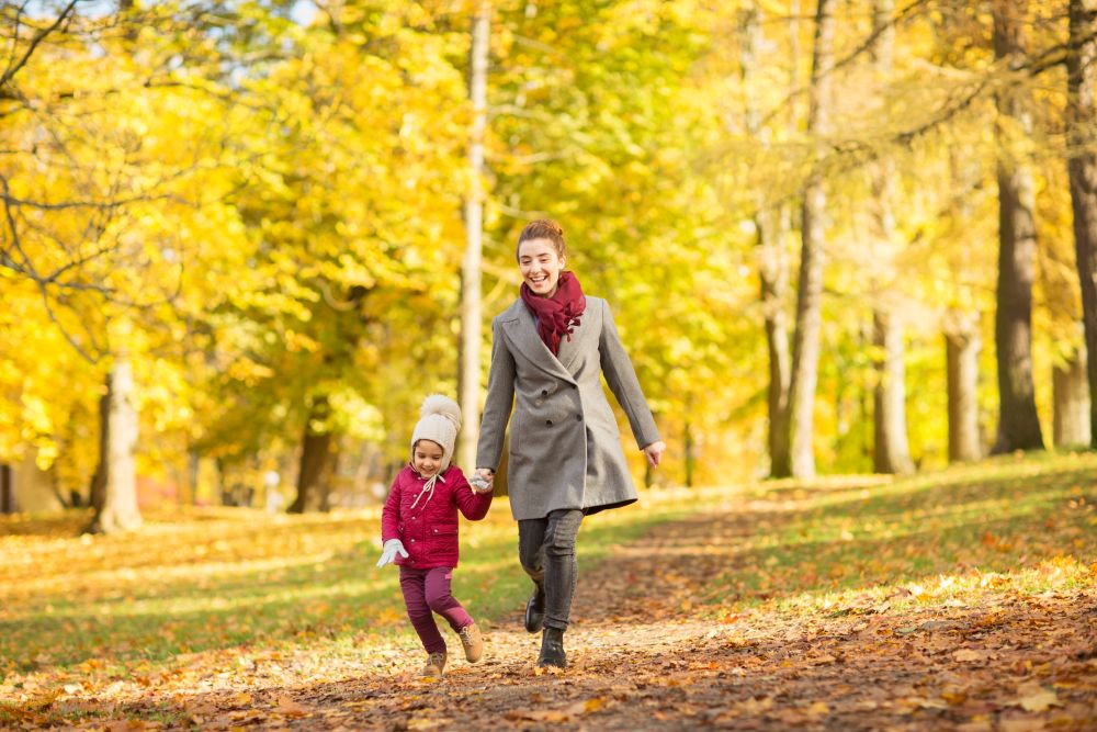 family, season and people concept - happy mother and little daughter walking along autumn park. happy mother and little daughter at autumn park