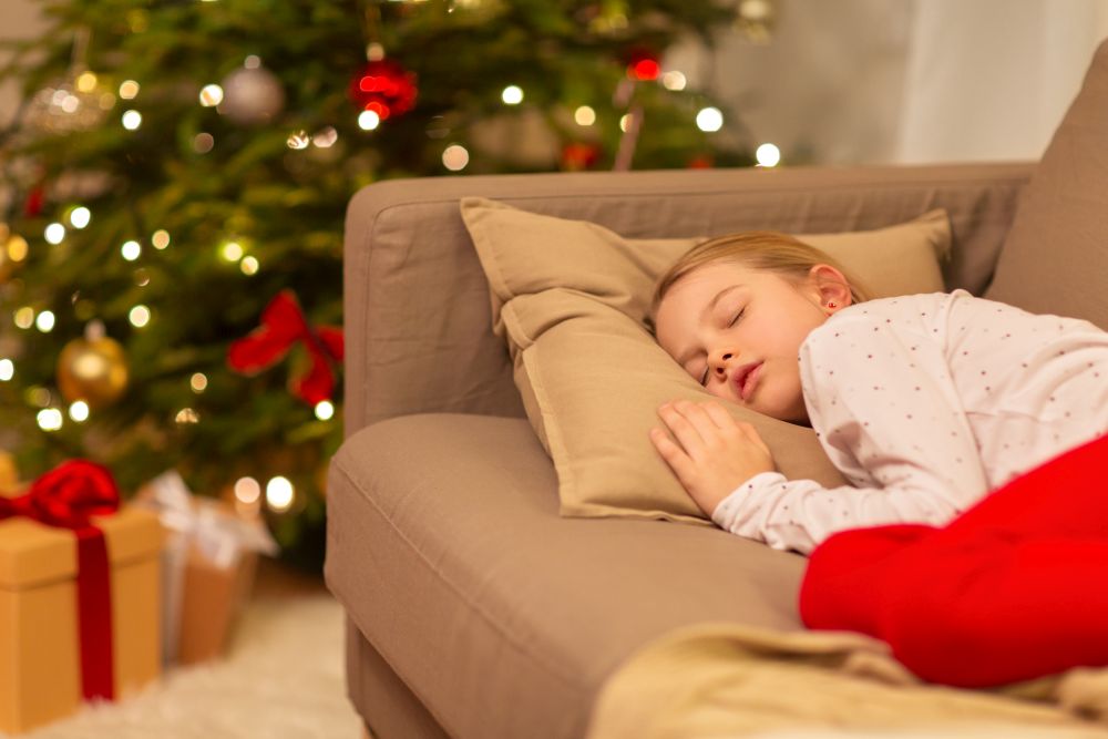 christmas, holidays and childhood concept - girl sleeping on sofa at home. girl sleeping on sofa at christmas