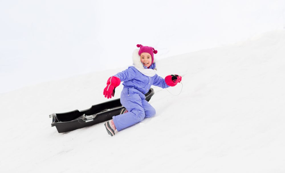 childhood, sledging and winter season concept - happy little girl with sled on snow hill. little girl with sled on snow hill in winter