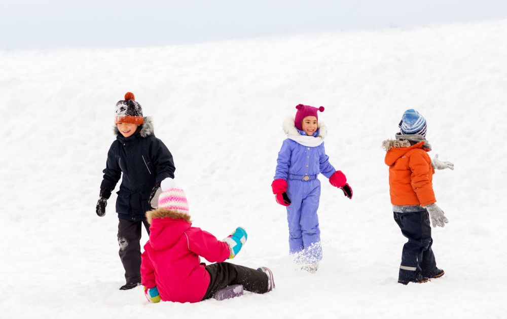 childhood, leisure and season concept - group of happy little kids in winter clothes playing outdoors. happy little kids playing outdoors in winter