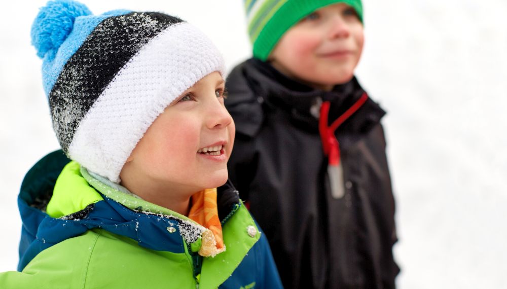 childhood, leisure and season concept - close up of happy little boys in winter clothes outdoors. close up of little boys in winter clothes outdoors