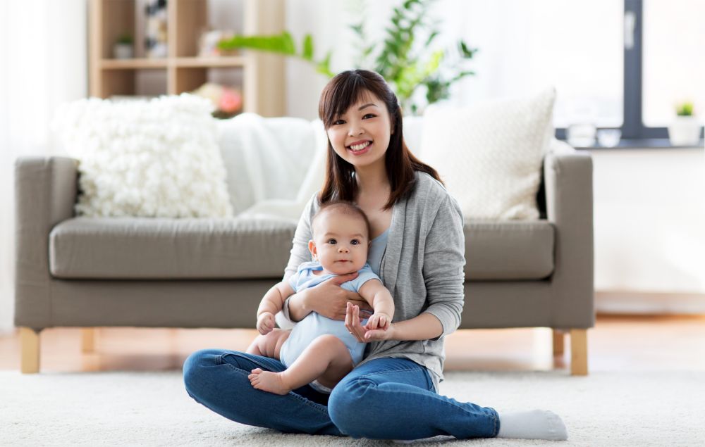 family and motherhood concept - happy smiling young asian mother with little baby at home. happy young mother with little baby at home