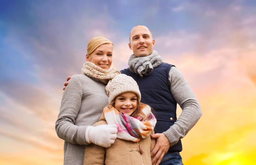 family, season and people concept - happy mother, father and daughter over evening sky background. happy family over evening sky background